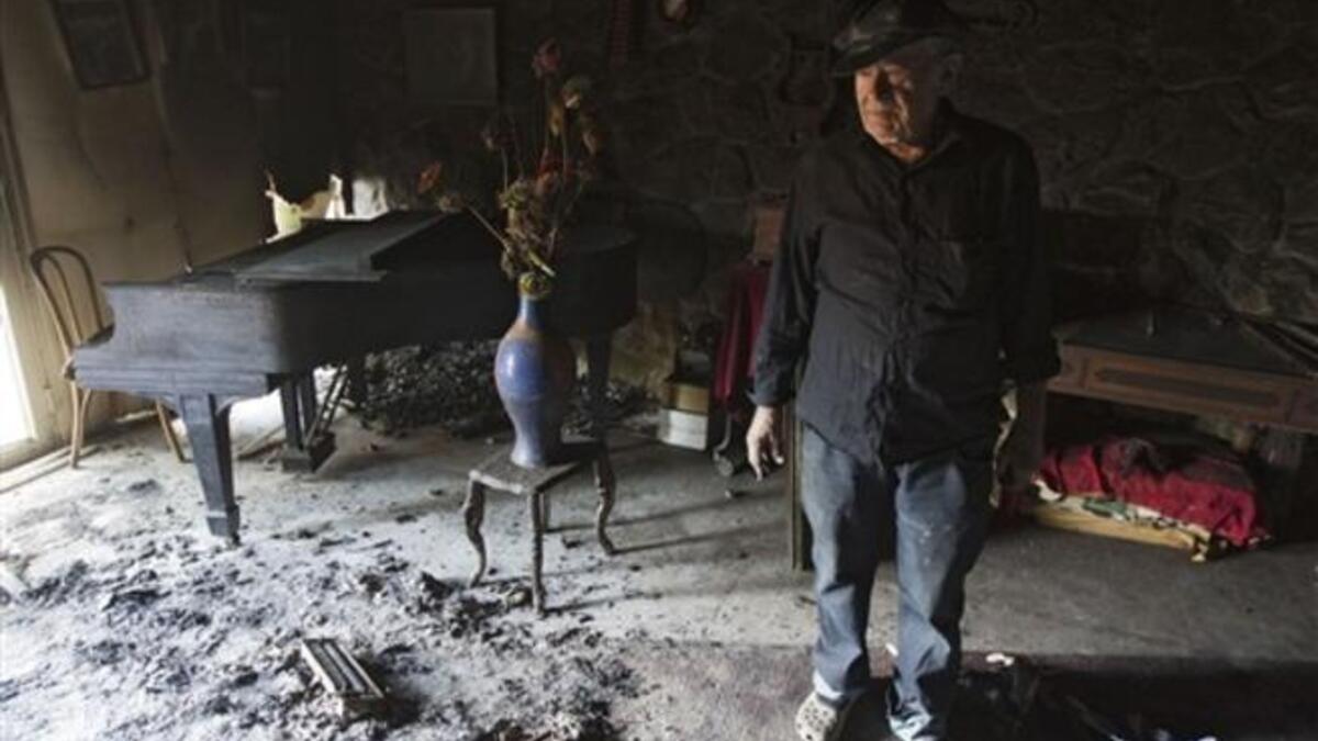 Israeli Nissan Cohen, 84, inspects his burnt Nisco Museum of Music boxes and Mechanical Music, in the artists village of Ein Hod near the northern city of Haifa, after a massive forest fire was finally brought under control, with the assistance of equipment and personnel from more than 16 countries.