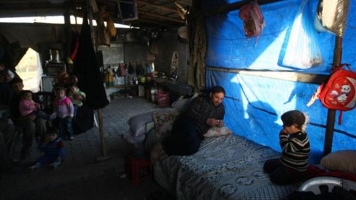 Members of a displaced Palestinian family sit outside their tent.