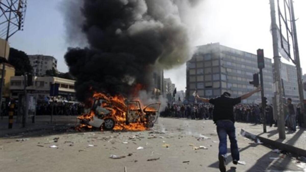 Supporters of the Future Movement gather as they watch the torched vehicle belonging to the Arabic language al-Jazeera satellite television station.