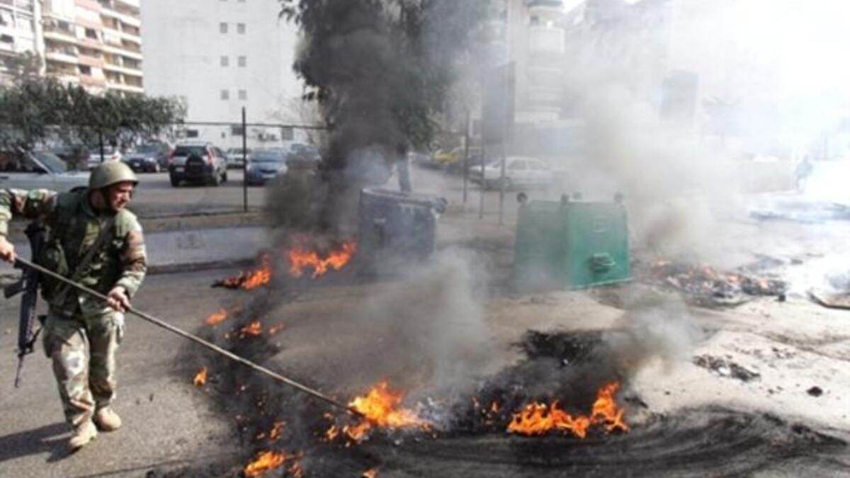 A Lebanese soldier disperses burning tires set alight by supporters of the Future Movement.