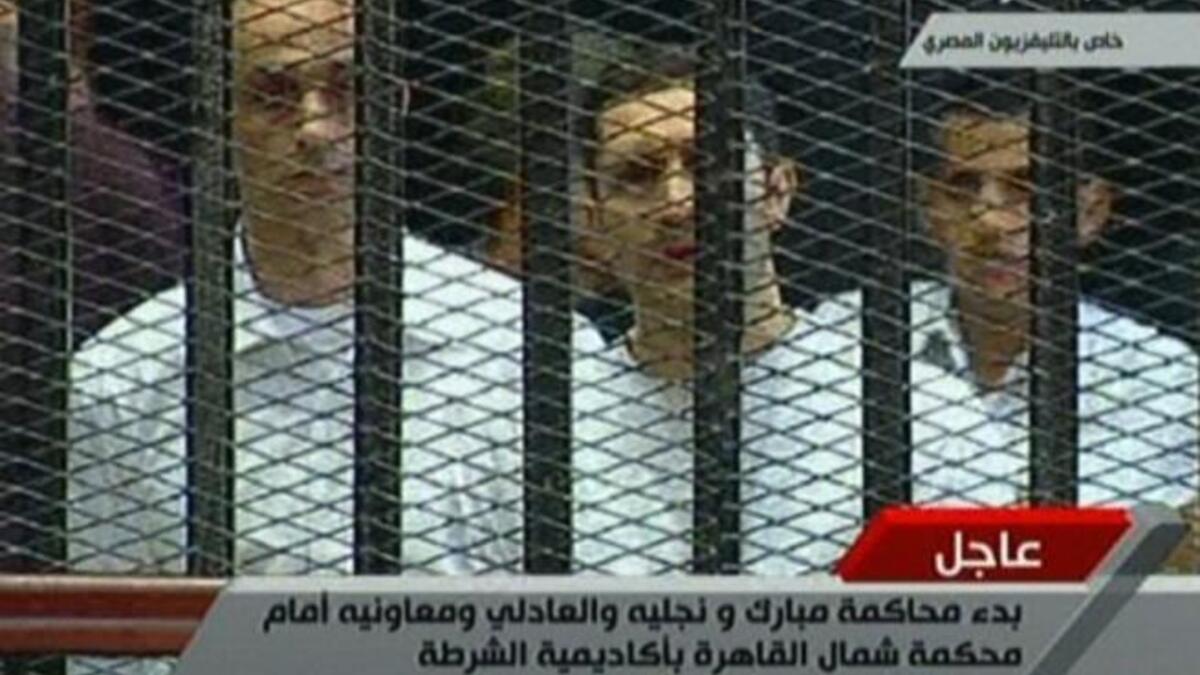 Alaa (C) and Gamal (L) Mubarak are seen in their 'family cage'. Bystanders observed Alaa to be clutching on to a Koran for much of the proceedings.