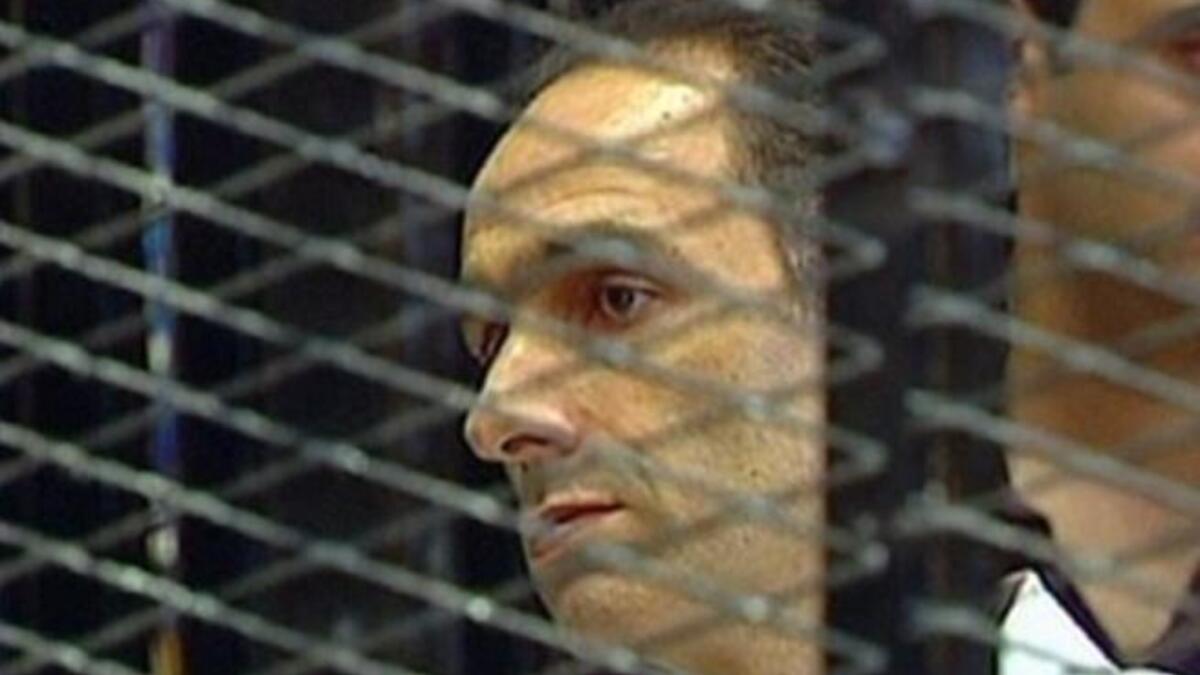 Gamal Mubarak is seen in a holding cell on the first day of his trial along with his brother and father, ousted Egyptian president Mubarak and other government officials. Father-on-trial said to be fidgety & squirming, even playing with his nose; some have irreverently cited him as 'picking' it.