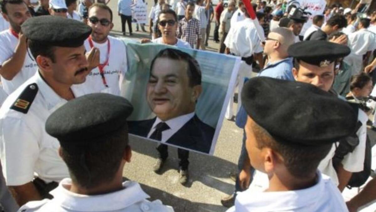 Egyptian supporters of former president Hosni Mubarak hold up his poster as they stand in front of the police on the opening day of his trial.