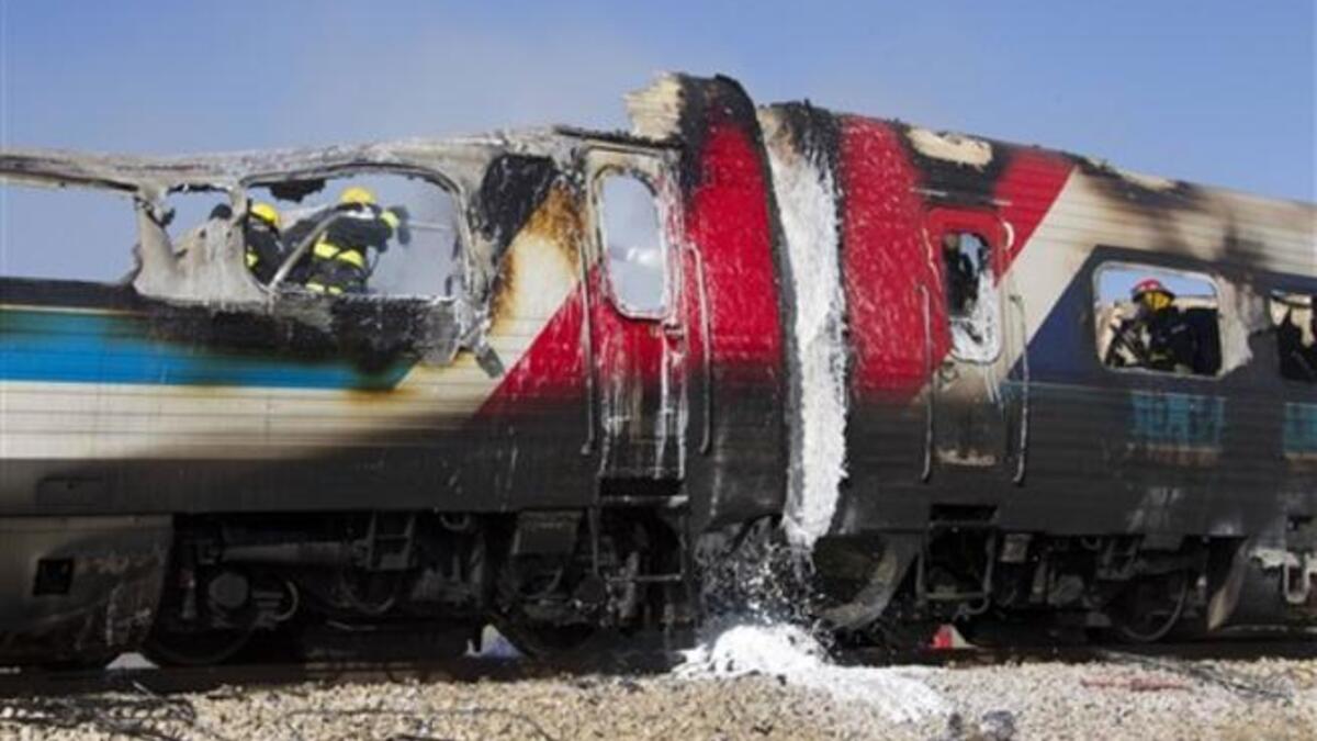 Israeli fire fighters spray water to extinguish the flames of a burning train coach near Kibbutz Shfaim, close to the Israeli city of Netanya.
