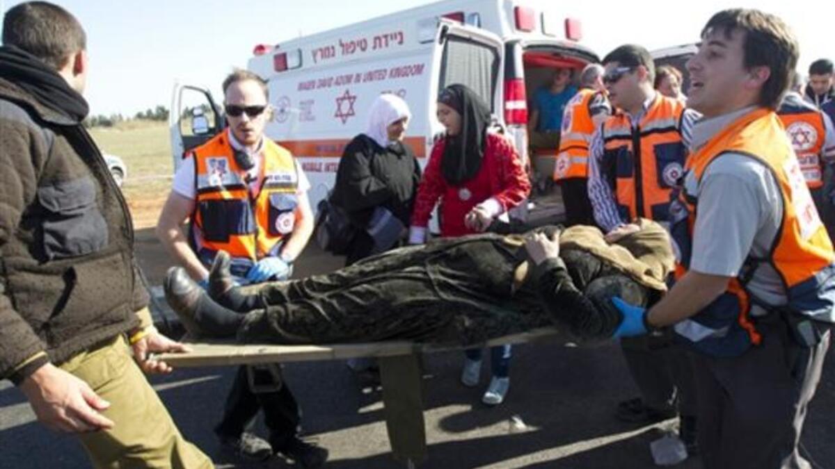 A wounded Arab Israeli woman is evacuated from a burning train coach by paramedics near Kibbutz Shfaim.