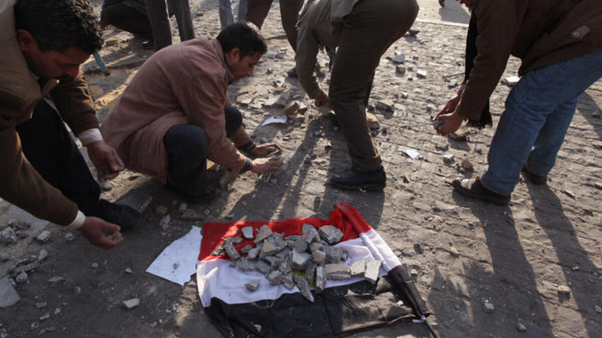 Anti-government protestors place broken paving stones on an Egyptian flag to throw at supporters of President Mubarak.