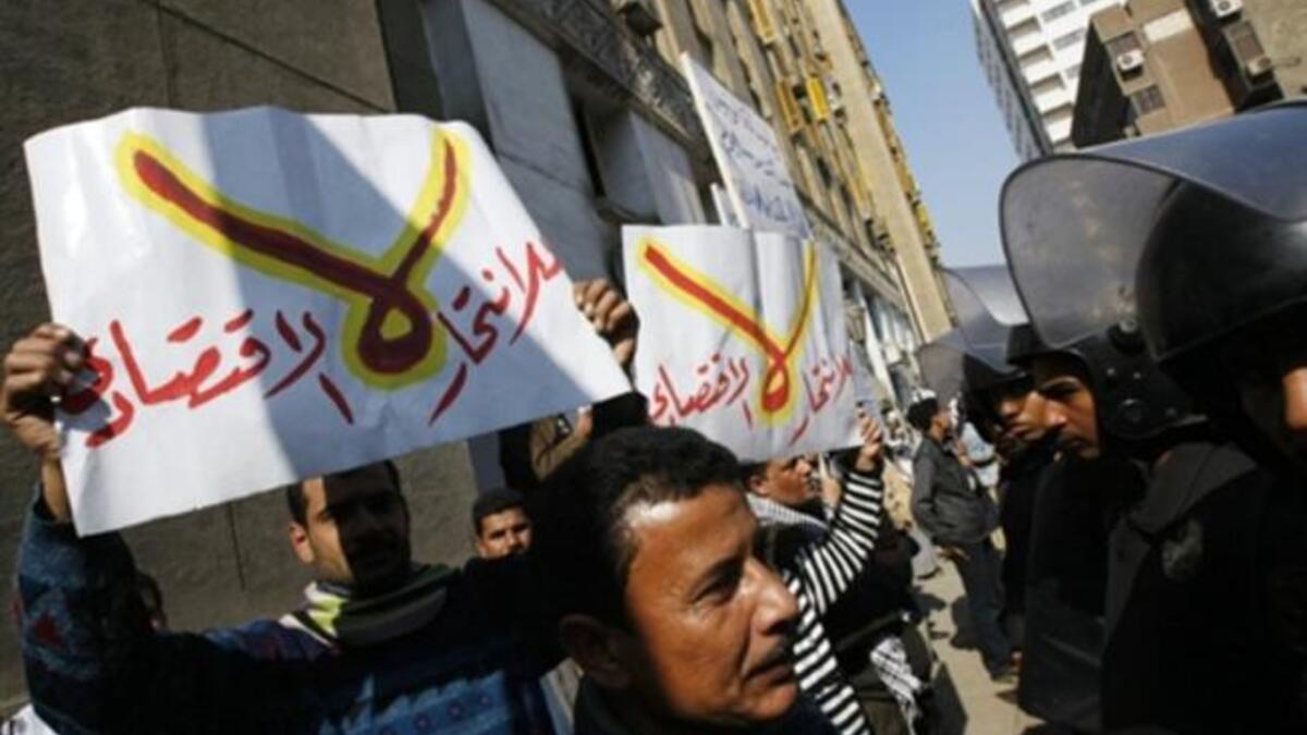 Egyptian riot policemen stop protesters from approaching the parliament building in downtown Cairo during a demonstration. Arabic writing on placards reads "No for economic suicide".