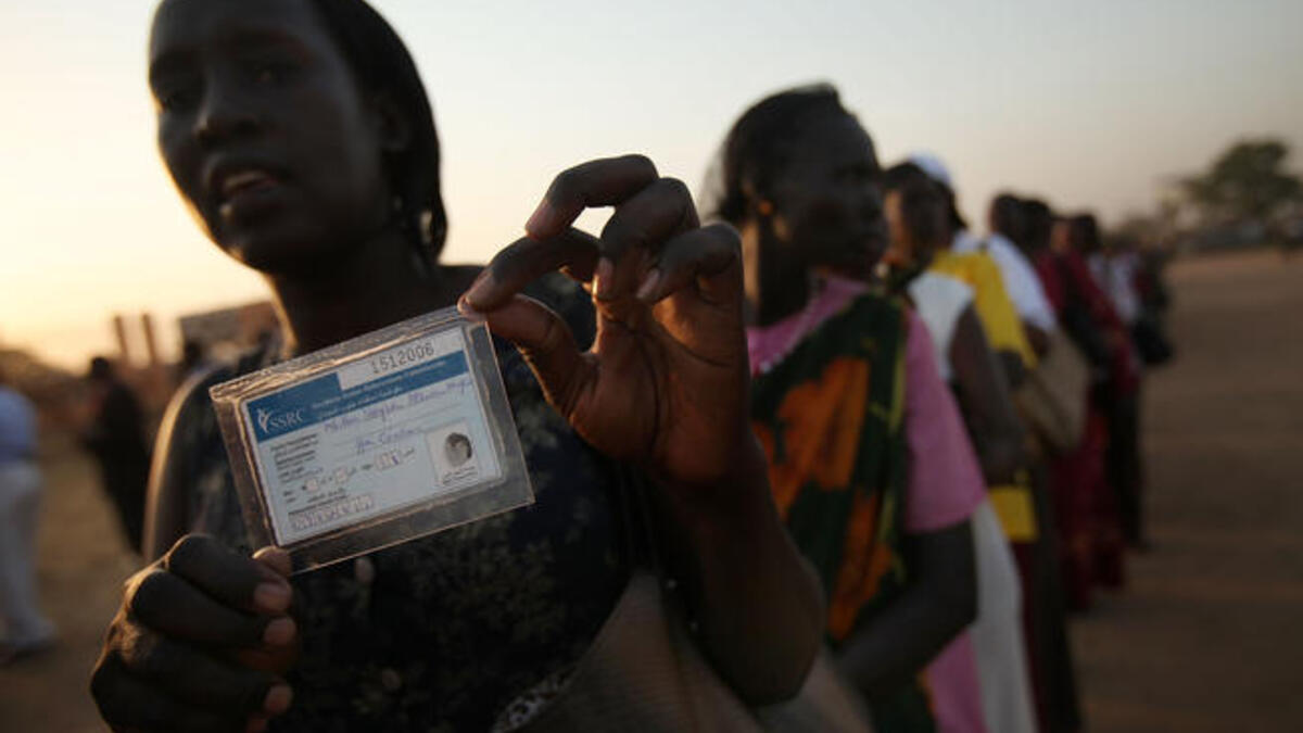 A woman displays her voting card while in line to vote.