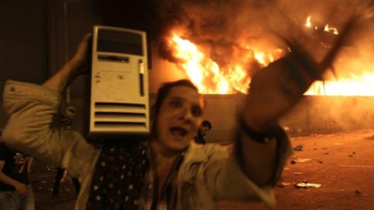 An Egyptian man loots a computer from the burning headquarters of the of the ruling National Democratic party.
