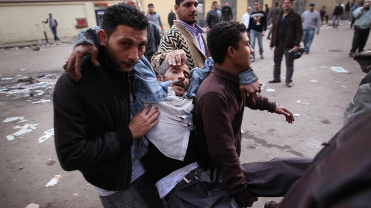 Protesters carry an injured man during clashes with riot police near Tahrir Square.