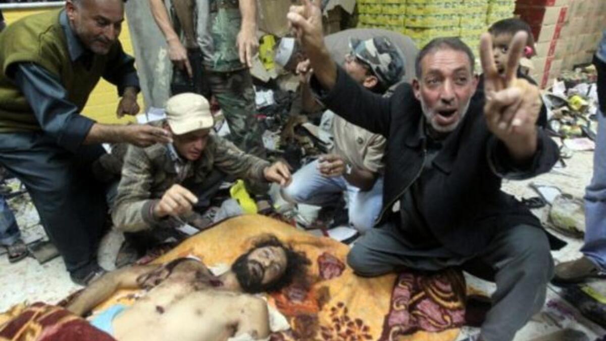 الليبيون يظهرون ابتهاجهم مجتمعين حول جثة المعتصم القذافي في مصراته. قتل المعتصم بعد والده حين داهم الثوار مخبأهما في سرت وقد كان المعتصم منافسا لأخيه سيف في وراثة حكم ليبيا.