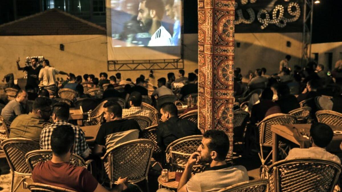 Palestinians watch on a big screen the Russia 2018 World Cup Group A football match between Russia and Egypt at at a coffeehouse in Gaza City.
