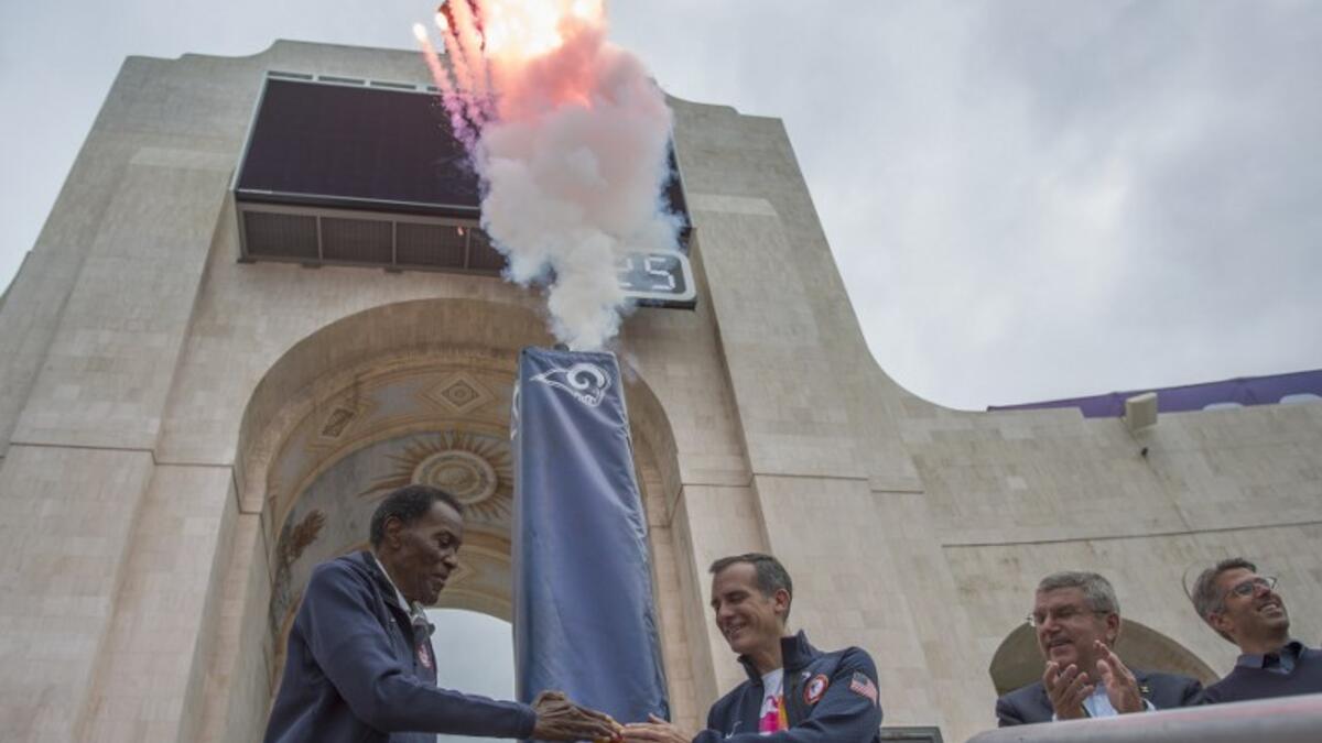 Olympic gold medalist Rafer Johnson (L), Los Angeles Mayor Eric Garcetti push the ignition switch to light the Los Angeles Memorial Coliseum's Olympic Cauldron as International Olympic Committee President Thomas Bach and LA 2028 Chairman Casey Wasserman (R) stand by on September 17, 2017 in Los Angeles.
DAVID MCNEW / AFP