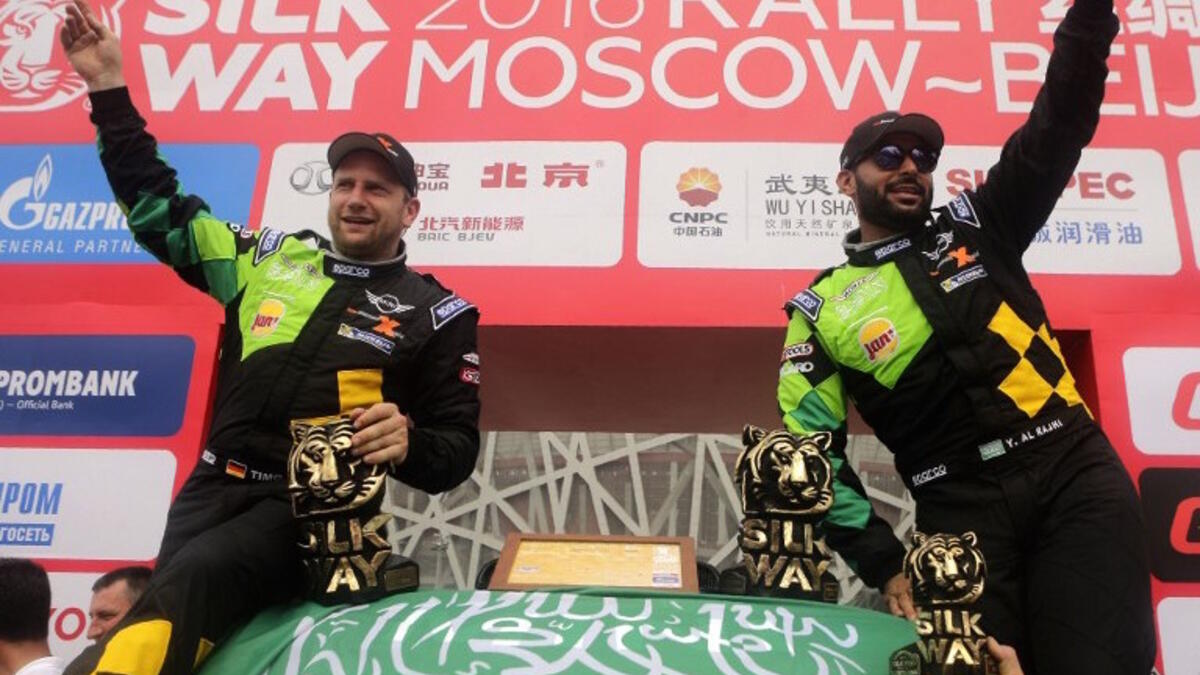 Mini team Yazeed Mohamed al-Rajhi an co-pilot Timoo Gottschalk celebrate with a Saudi flag their second place podium of the Silk Way Rally in Beijing on July 24, 2016.
PATRICK BAZ / AFP