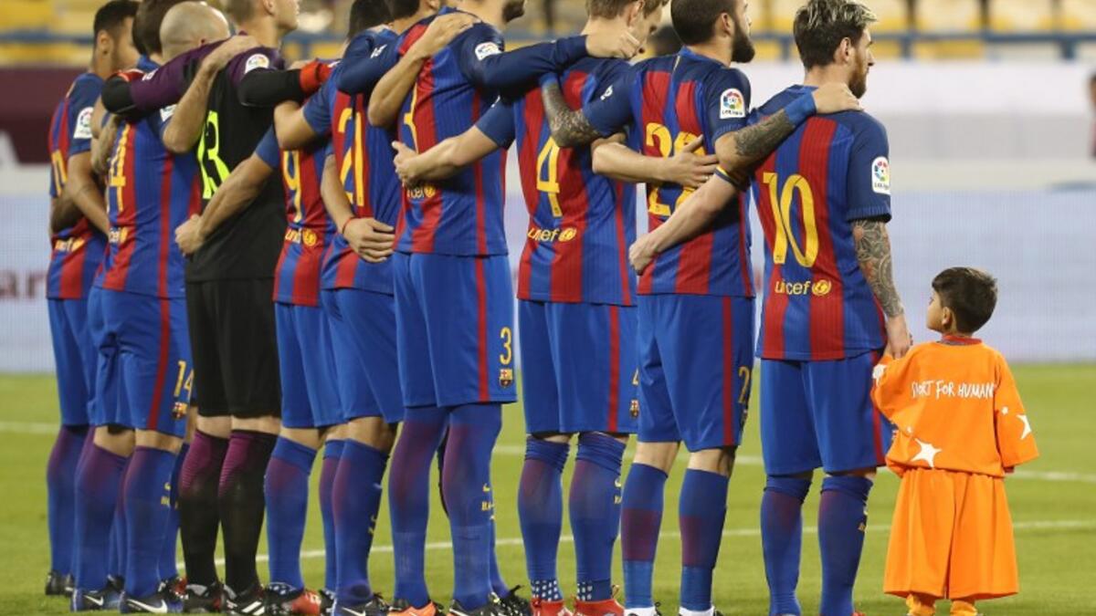 Afghan boy Murtaza Ahmadi stands with the FC Barcelona team on the pitch before the start of a friendly football match against Saudi Arabia's Al-Ahli FC on December 13, 2016 in the Qatari capital Doha. The Spanish club's last major obligation of its four year shirt sponsorship deal with Qatar Airways. KARIM JAAFAR / AFP