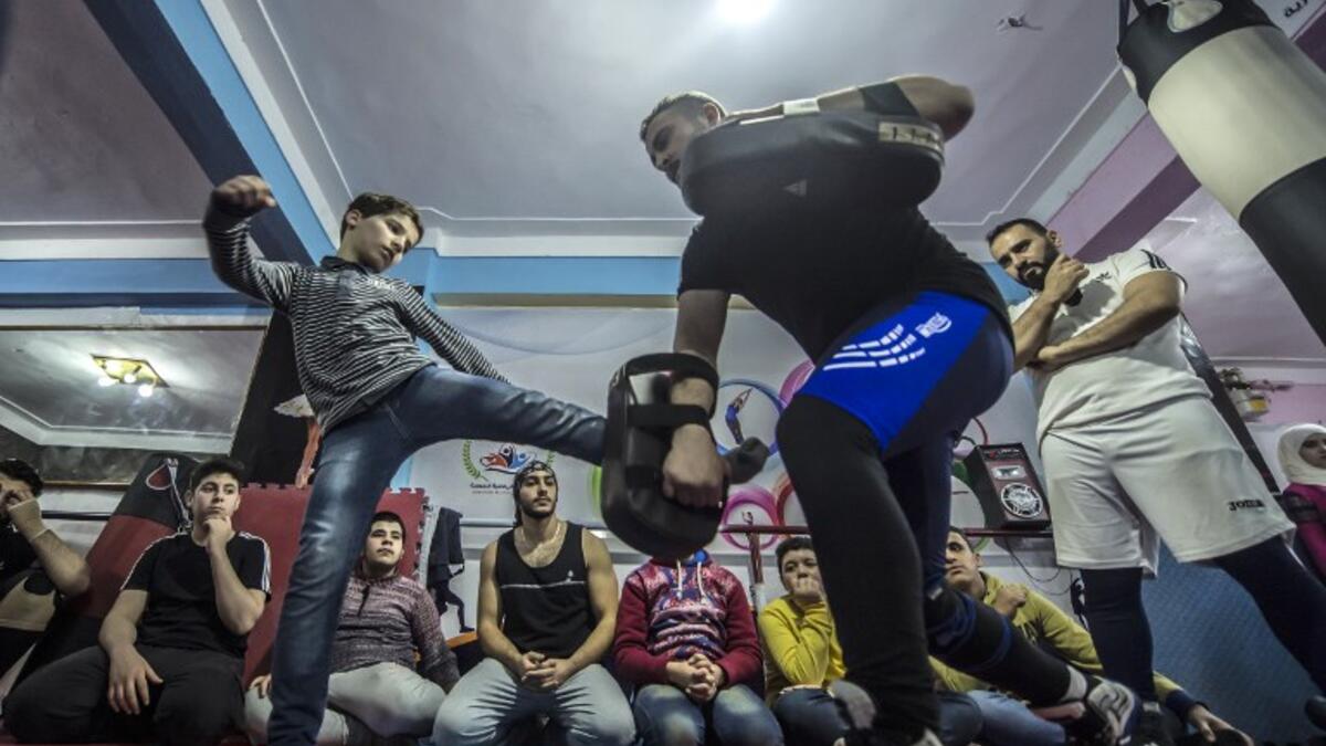 Syrian refugee Amir al-Awad (R) watches as Adel Bazmawi (C) teaches martial arts to youth at the academy in Egypt's Alexandria on Jan 4, 2018. The academy is squeezed into just 30 square metres, in a modestly equipped hall at the bottom of a residential building. The project began in 2016 with just $430 at the time.

KHALED DESOUKI / AFP