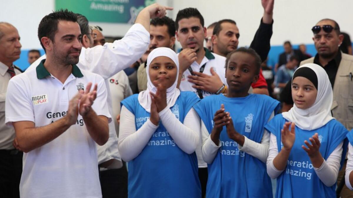 Former Barcelona football player Xavi Hernandez (L), who currently plays for Al-Sadd in the Qatar Stars League, claps as he attends a training session during his visit to the al-Baqaa Palestinian refugee camp near Amman on September 29, 2016.
Khalil MAZRAAWI / AFP