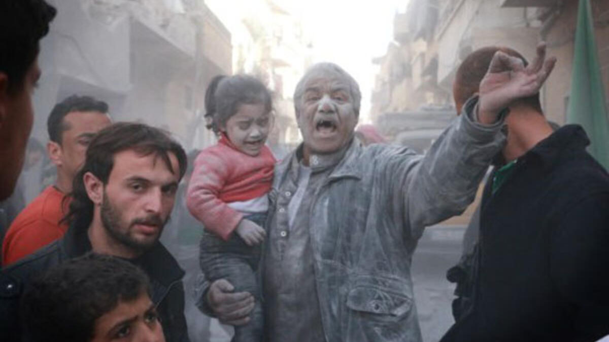 اب سوري يحمل طفلته بعد نجاتهم من قصف بالبراميل المتفجرة من قبل الطيران النظامي في حلب/أ.ف.ب