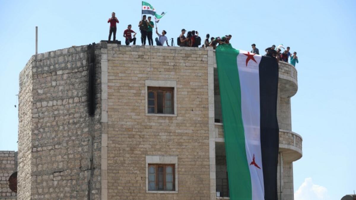 Syrian protesters wave the flag of the opposition as they demonstrate against the regime and its ally Russia, in the rebel-held city of Idlib on September 7, 2018. (OMAR HAJ KADOUR / AFP)