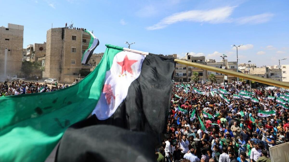 Syrian protesters wave the flag of the opposition as they demonstrate against the regime and its ally Russia, in the rebel-held city of Idlib on September 7, 2018. (OMAR HAJ KADOUR / AFP)