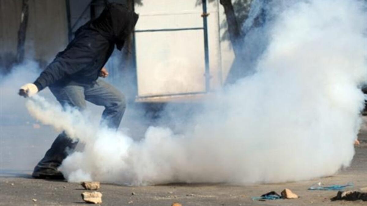 A Tunisian demonstrator prepares to throw a tear-gas canister during clashes with security forces.