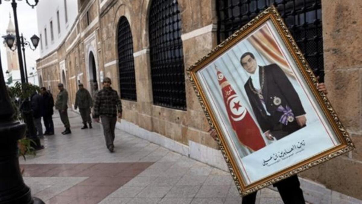 A Tunisian employee of the Prime ministry removes a portrait of former Tunisian president Ben Ali.