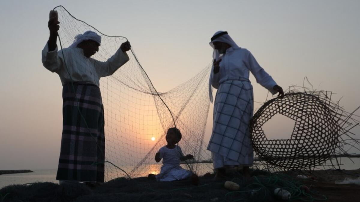 Emirati men train a child on handicraft industries during the Dalma Sailing Festival. (KARIM SAHIB / AFP)