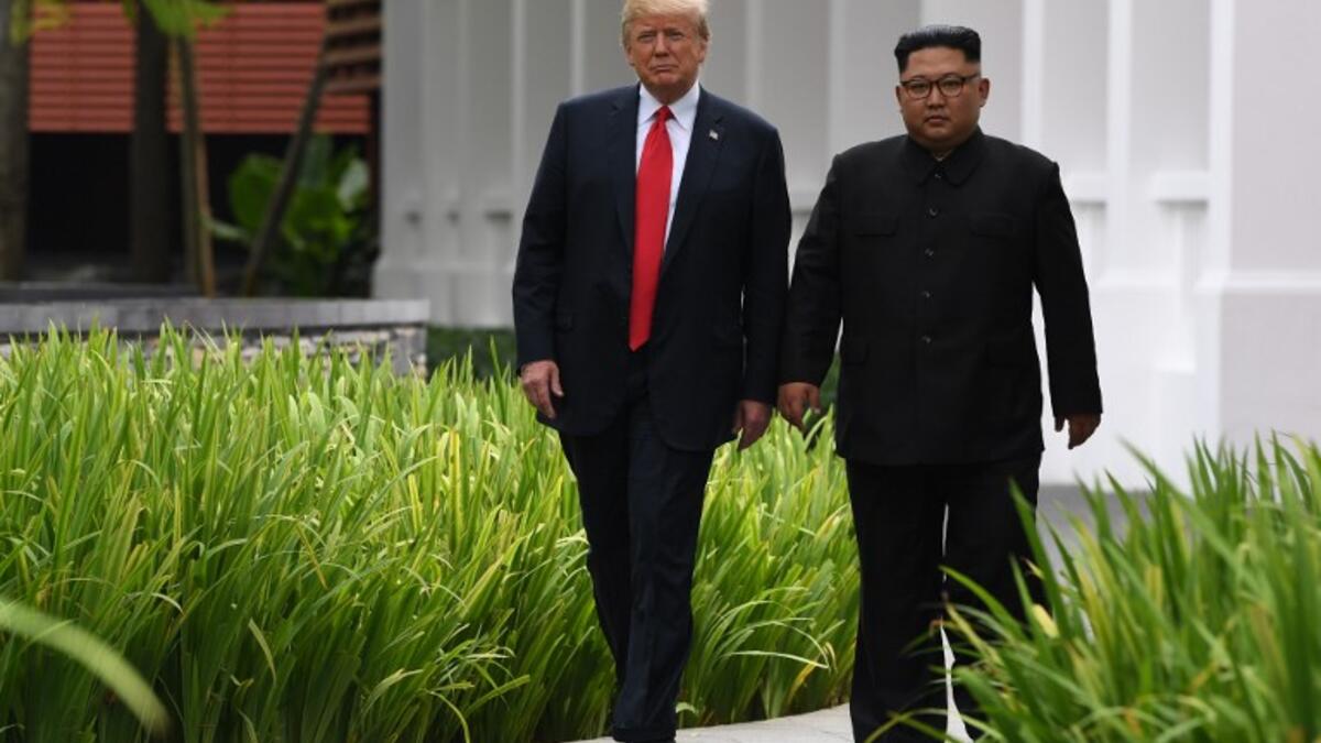 North Korea's leader Kim Jong Un (R) walks with US President Donald Trump (L) during a break in talks at their historic US-North Korea summit, at the Capella Hotel on Sentosa island in Singapore on June 12, 2018. (SAUL LOEB / AFP)