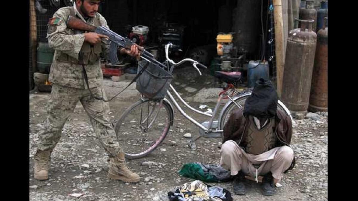 رجل أمن أفغاني يصوب سلاحه تجاه رجل اتهم بتخطيطه لتفجير انتحاري في مدينة جلال أباد بأفغانستان.