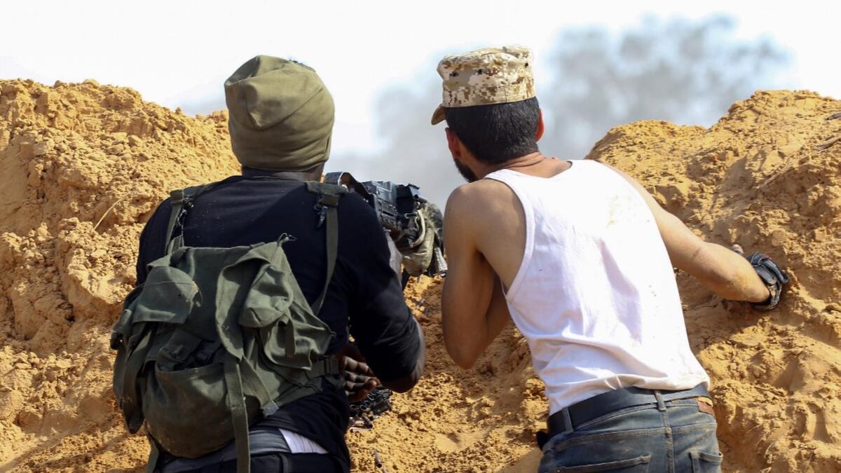 Libyan fighters loyal to the Government of National Accord (GNA) take cover behind a dirt barrier during clashes with forces loyal to strongman Khalifa Haftar south of the capital Tripoli's suburb of Ain Zara, on April 10, 2019. Mahmud TURKIA / AFP