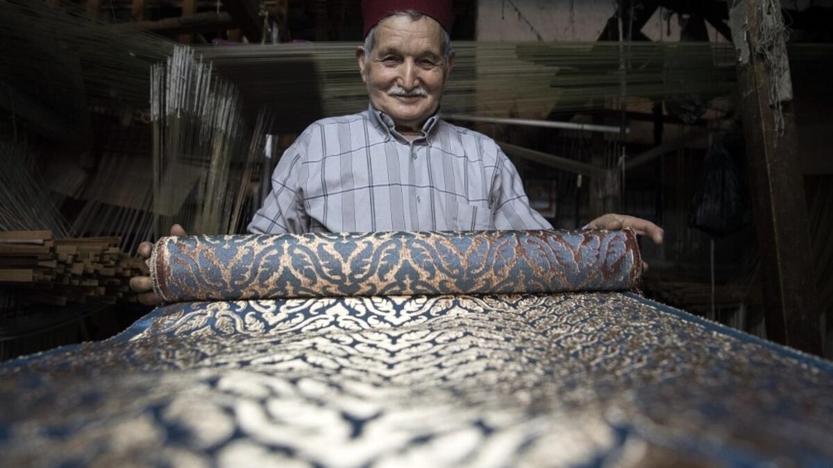 Abdelkader Ouazzani, the last of Morocco's brocade master weavers, displays tapestry at his workshop in the old city of Fez on April 10, 2019. His skilfull hands intricately create shimmering silk fabrics, enhanced with gold or silver thread, for bridal jewellery, designer creations or high-end furnishings. FADEL SENNA / AFP