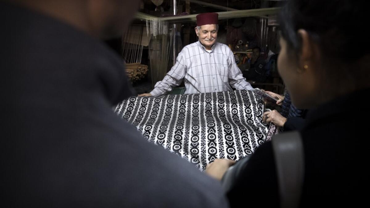 Abdelkader Ouazzani, the last of Morocco's brocade master weavers, displays tapestry at his workshop in the old city of Fez on April 10, 2019. His skilfull hands intricately create shimmering silk fabrics, enhanced with gold or silver thread, for bridal jewellery, designer creations or high-end furnishings. FADEL SENNA / AFP