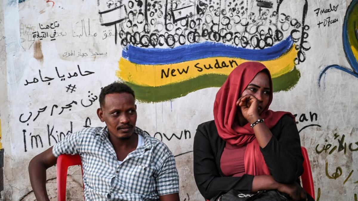 Sudanese protestors sit in front of a recently painted mural during a protest outside the army complex in the capital Khartoum OZAN KOSE / AFP