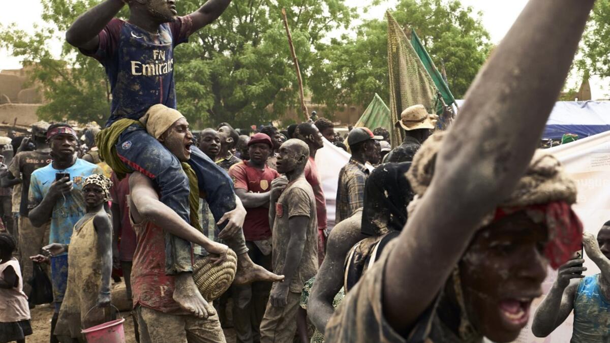 People take part in the annual rendering of the Great Mosque of Djenne in central Mali on April 28, 2019. Several thousand residents of the historic central Malian city of Djenne, a UNESCO World Heritage site, took part in the annual rendering ceremony of the Grand Mosque, which will now be powered by solar electricity. The rendering of the building with banco (a mixture of soil and water, with rice bran, shea butter and baobab powder) made by the city's inhabitants, helps to protect the mosque from bad wea