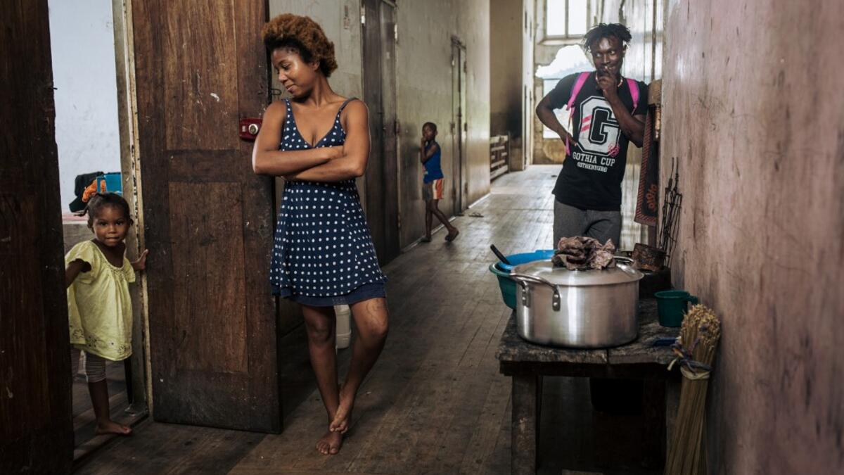 Willy, Jessica and a child, inhabitants of the roca Agostinho Neto, an abandoned cocoa plantation of Sao Tome and Principe, wait in a hall, of the hospital of the roca on May 12, 2019.  Alexis HUGUET / AFP