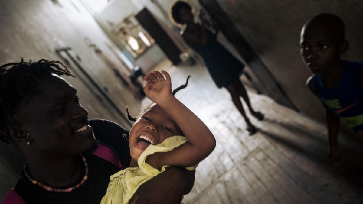 Willy, an inhabitant of the roca Agostinho Neto, an abandoned cocoa plantation of Sao Tome and Principe, plays with a child in a hall, of the hospital of the roca on May 29, 2019. Alexis HUGUET / AFP