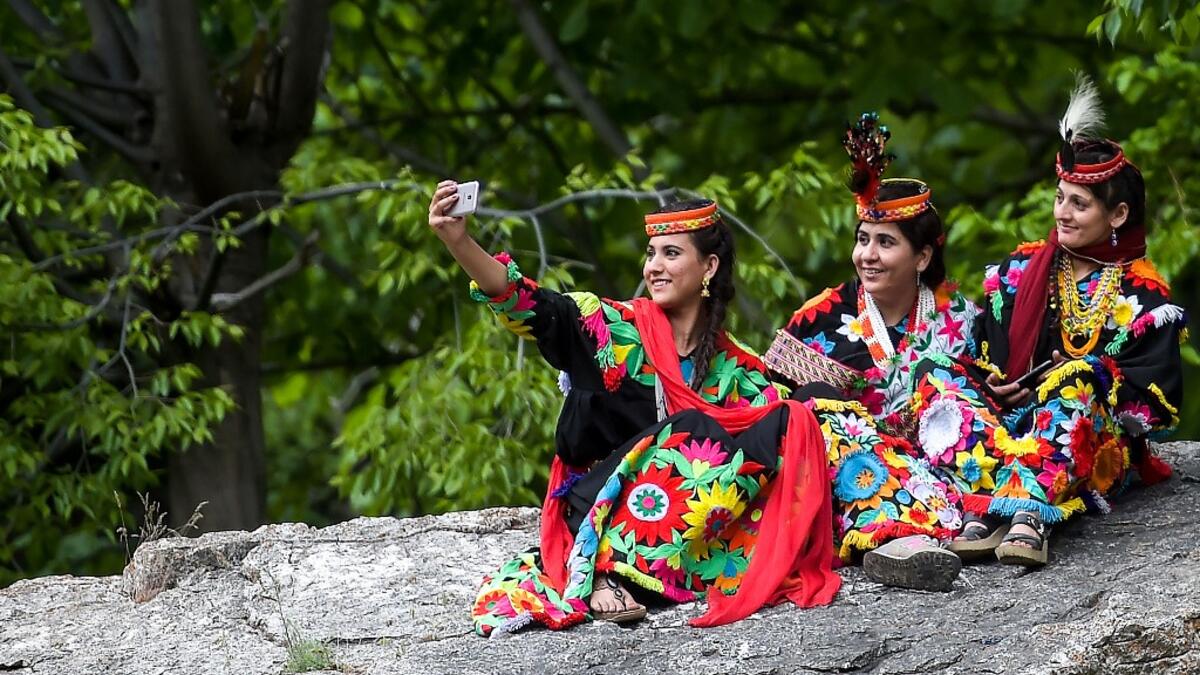 In a remote valley in Pakistan dozens of Kalash minority women dance to celebrate spring's arrival -- but as a gaggle of men scramble to catch them on camera, the community warns an influx of domestic tourists is threatening their unique traditions.  AAMIR QURESHI / AFP