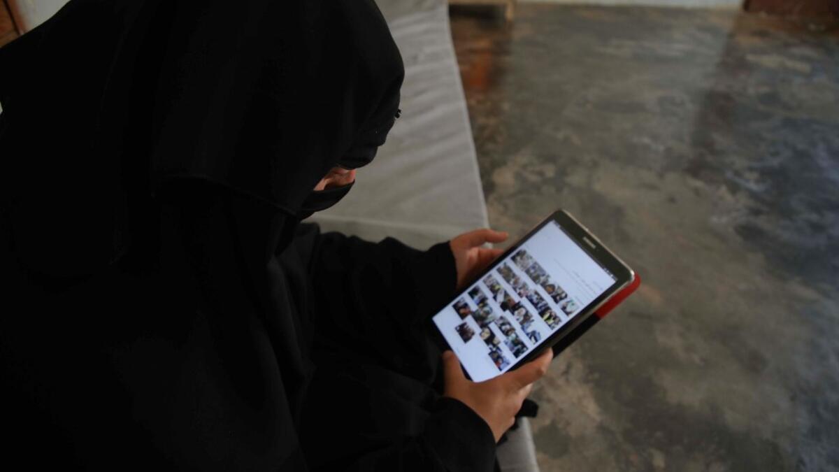 Hasna Dbeis, a 30-year-old former detainee in a Syrian-regime jail, looks at photographs on an electronic tablet device at her home  Aaref WATAD / AFP