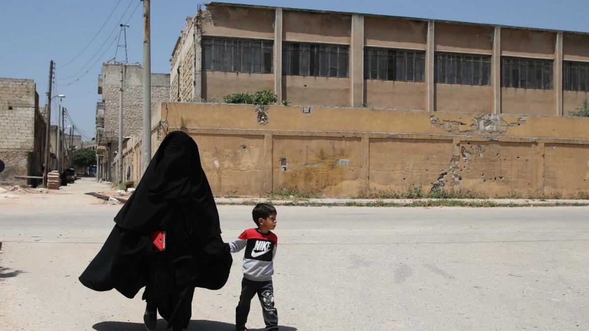 Hasna Dbeis, a 30-year-old former detainee in a Syrian-regime jail, holds her son Mohammad's hand, as they walk in the town of Maarat Nasrin, in the rebel-held part of the Syrian Idlib province  Aaref WATAD / AFP