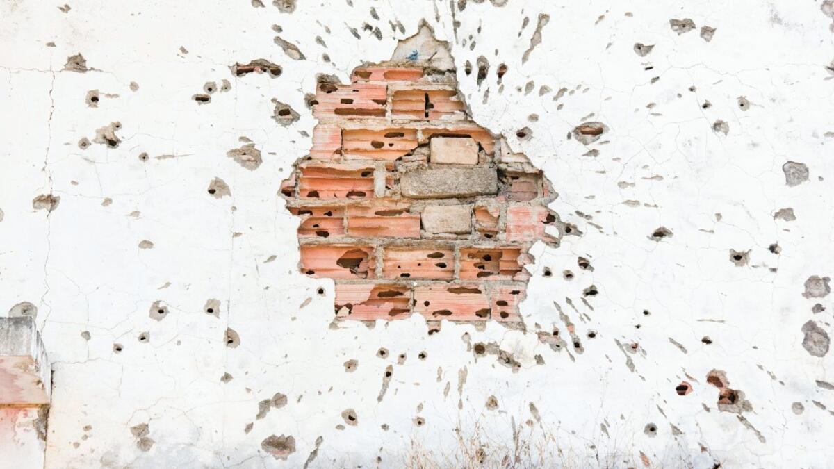 This picture shows a detail of a bullet-riddled brick wall, damaged during the Angolan civil war, in Kuito, Bie Province in Angola.  RODGER BOSCH / AFP