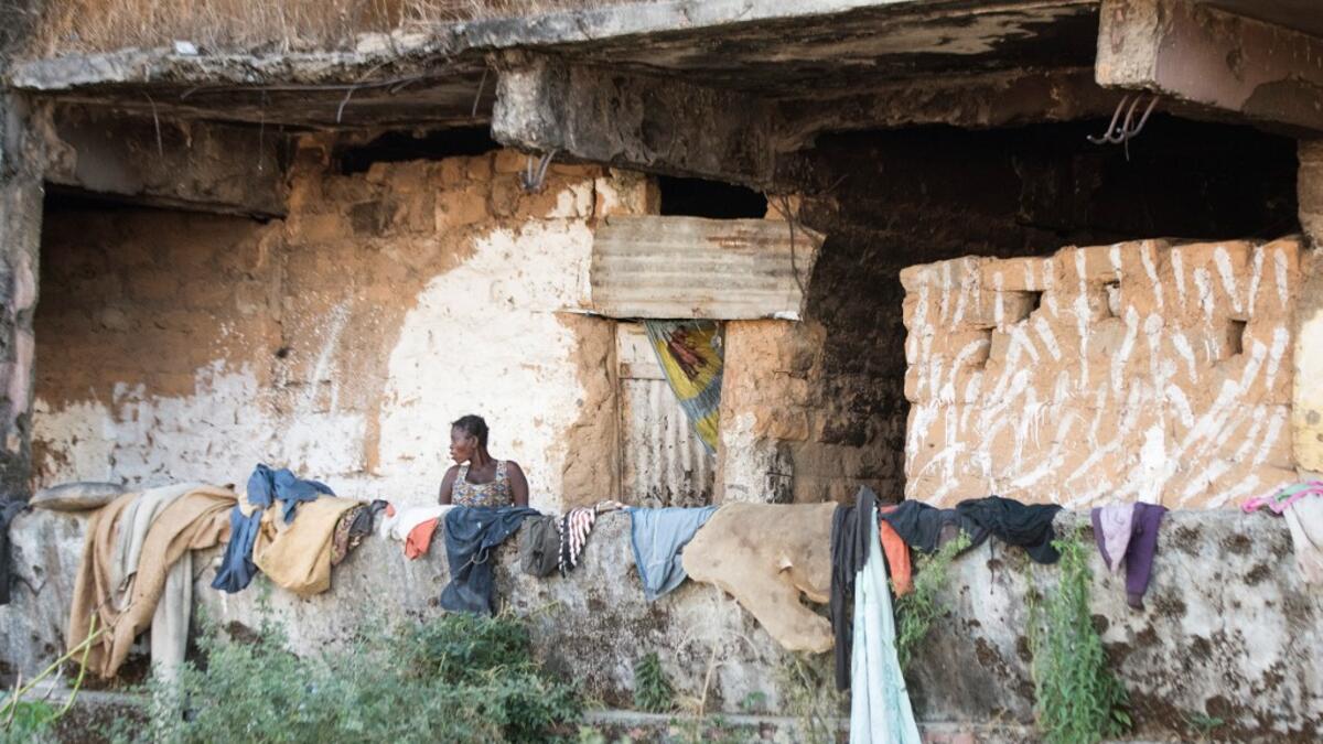 A homeless woman living in a derelict building, damaged during the Angolan civil war, stands by clothes left to dry on its wall RODGER BOSCH / AFP