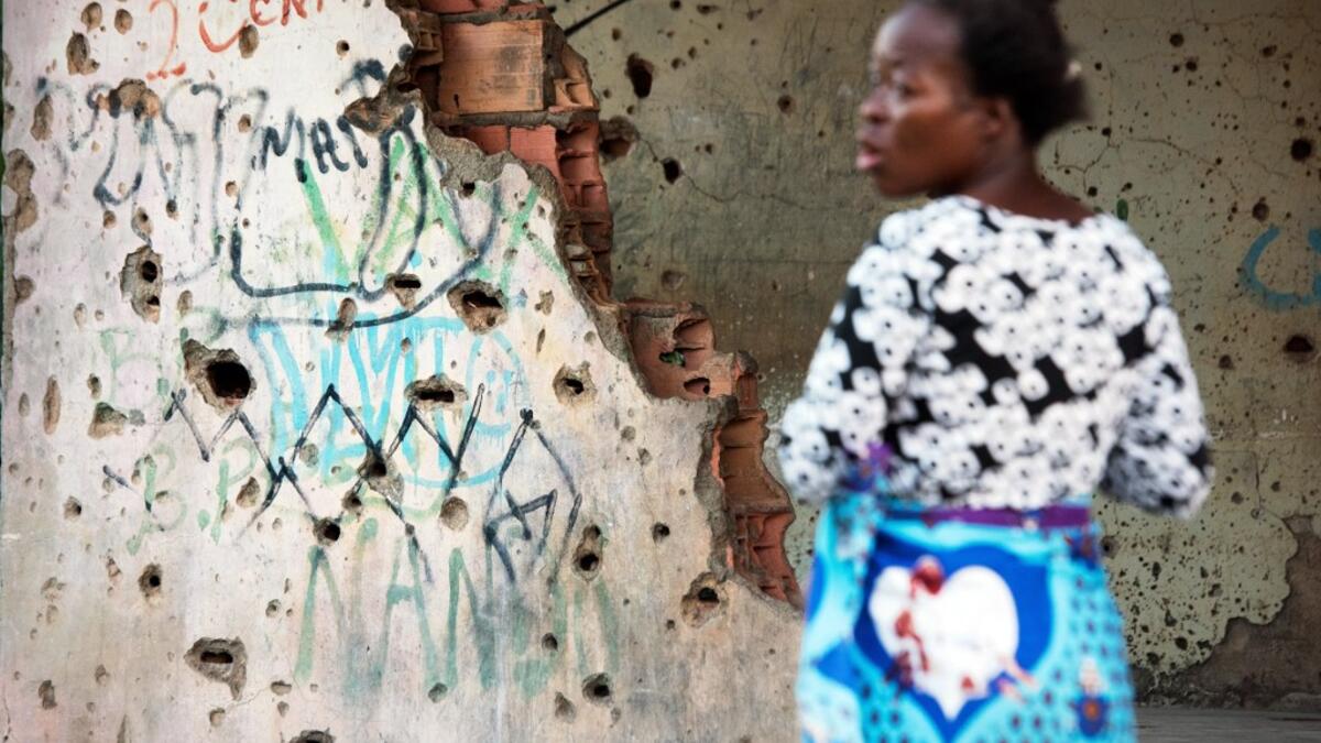 A woman, living in the bullet-riddled and graffiti-covered building that used to house Jonas Savimbi, leader of the rebel UNITA movement during the Angolan civil war, calls out, in Kuito, Bie Province in Angola. RODGER BOSCH / AFP