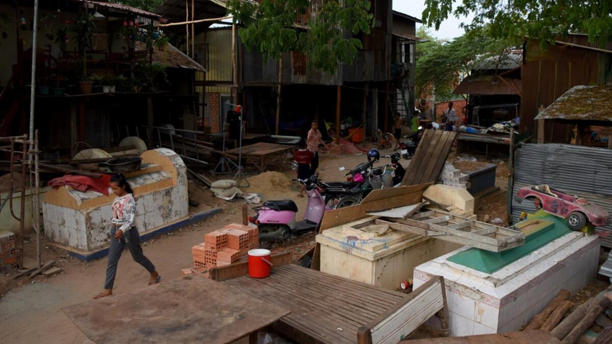 This picture  shows a woman walking past graves in Phnom Penh.  TANG CHHIN Sothy / AFP