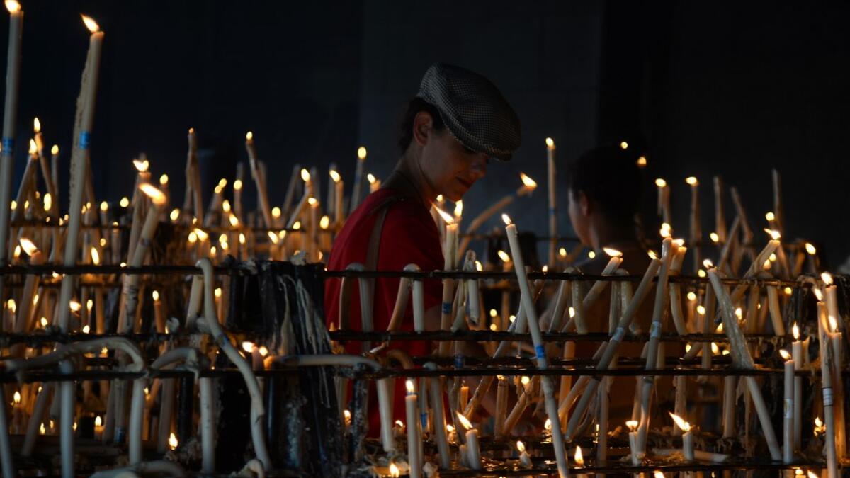 A pilgrim lights a candle at the church of the village of El Rocio.  CRISTINA QUICLER / AFP