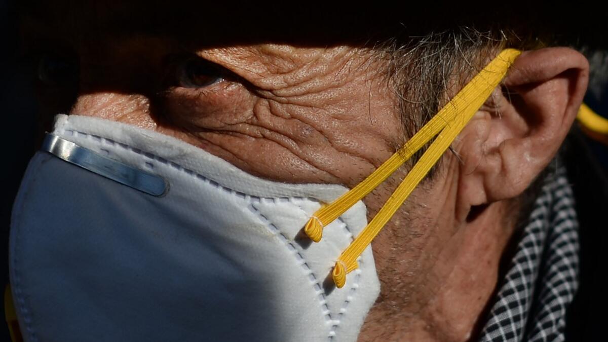 A pilgrim wearing a mask awaits the effigy of the Rocio Virgin during a procession at the village of El Rocio  CRISTINA QUICLER / AFP