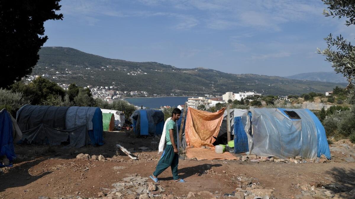 A migrant walks to take a shower at the makeshift refugee camp above the city of Vathy on the island of Samos early. LOUISA GOULIAMAKI / AFP