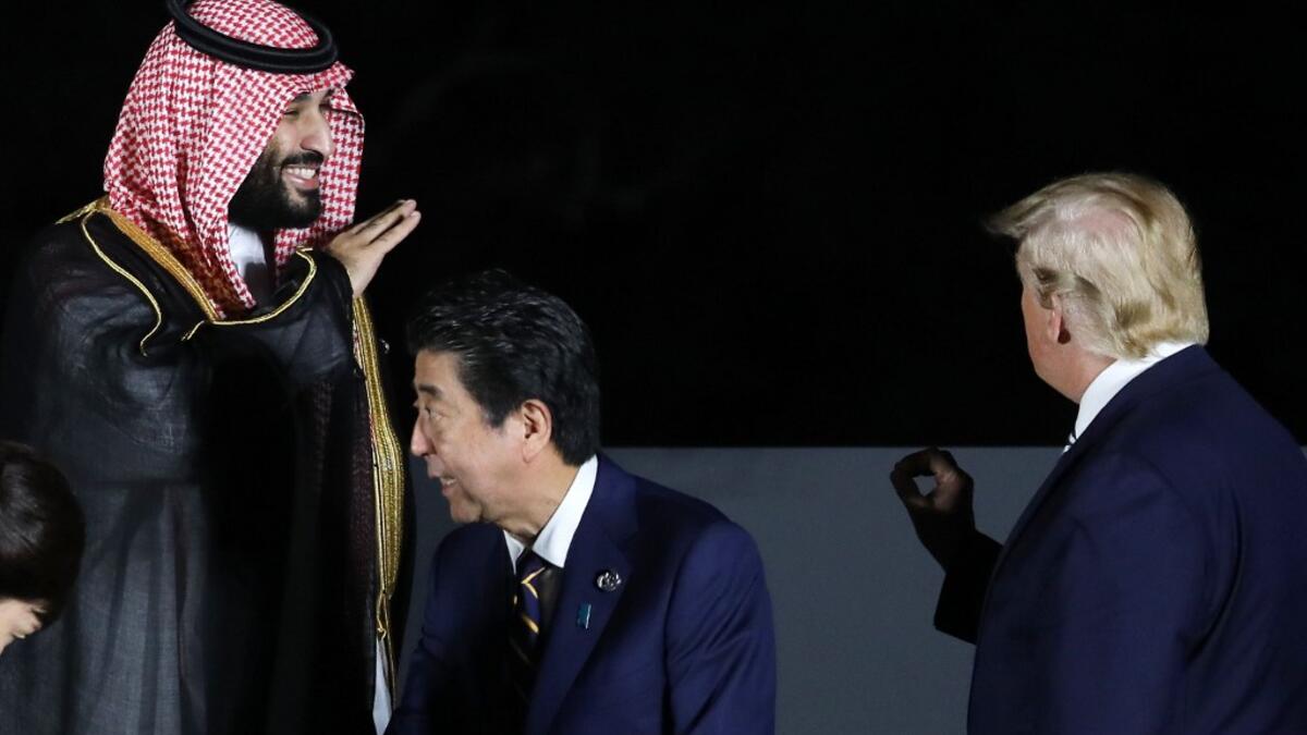 US President Donald Trump (R) and Saudi Crown Prince Mohammed bin Salman (L) gesture next to Japan's Prime Minister Shinzo Abe (C) and his wife Akie as they pose for a group photo during the G20 Summit in Osaka on June 28, 2019.  Dominique JACOVIDES / POOL / AFP
