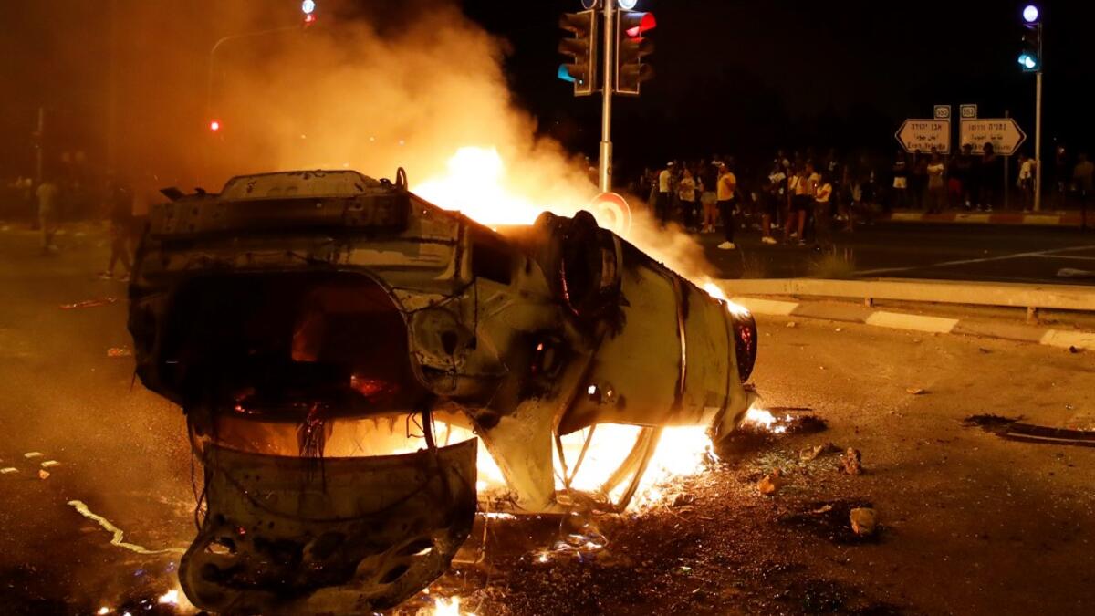 A burning and overturned police car blocks an entrance to the Israeli coastal city of Netanya , during a protest against the killing of Solomon Tekah, a young man of Ethiopian origin, who was killed by an off-duty police officer.  JACK GUEZ / AFP