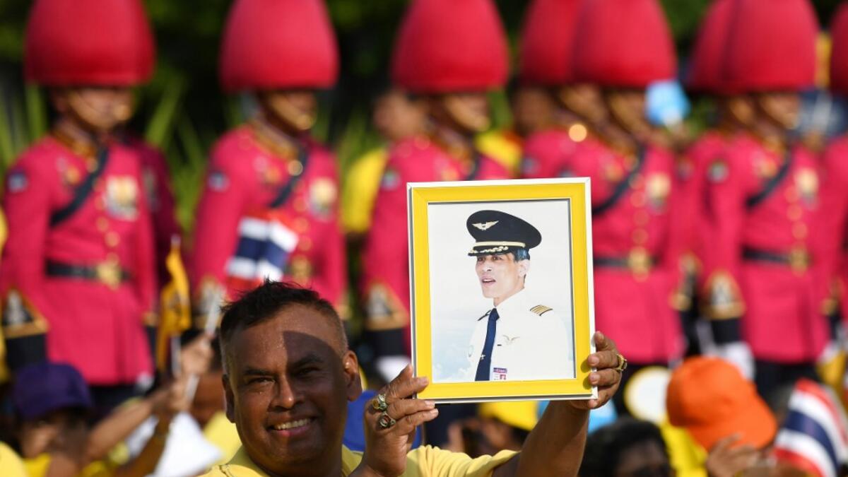 A man holds a portrait of Thailand's King Maha Vajiralongkorn as he waits for the King and Queen Suthida to appear on the balcony of Suddhaisavarya Prasad Hall of the Grand Palace for a public audience on the final day of his royal coronation in Bangkok on May 6, 2019.  Manan VATSYAYANA / AFP