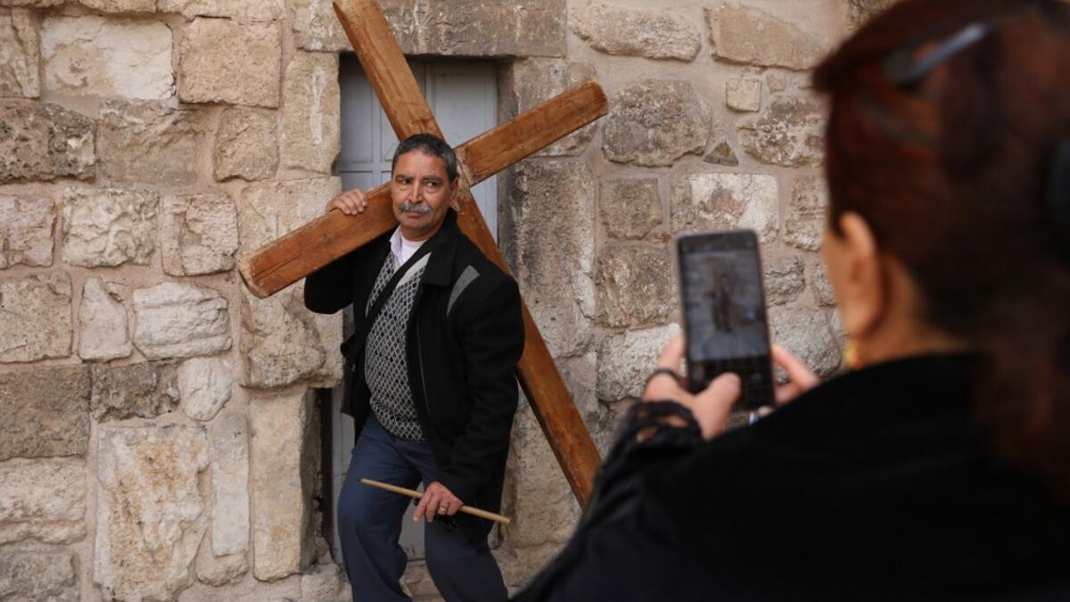 A Coptic Orthodox pilgrim poses for a picture as he carries a wooden cross at the church of the Holy Sepulchre in Jerusalem's Old City, on April 25, 2019 during the Orthodox Holy Week.  GALI TIBBON / AFP